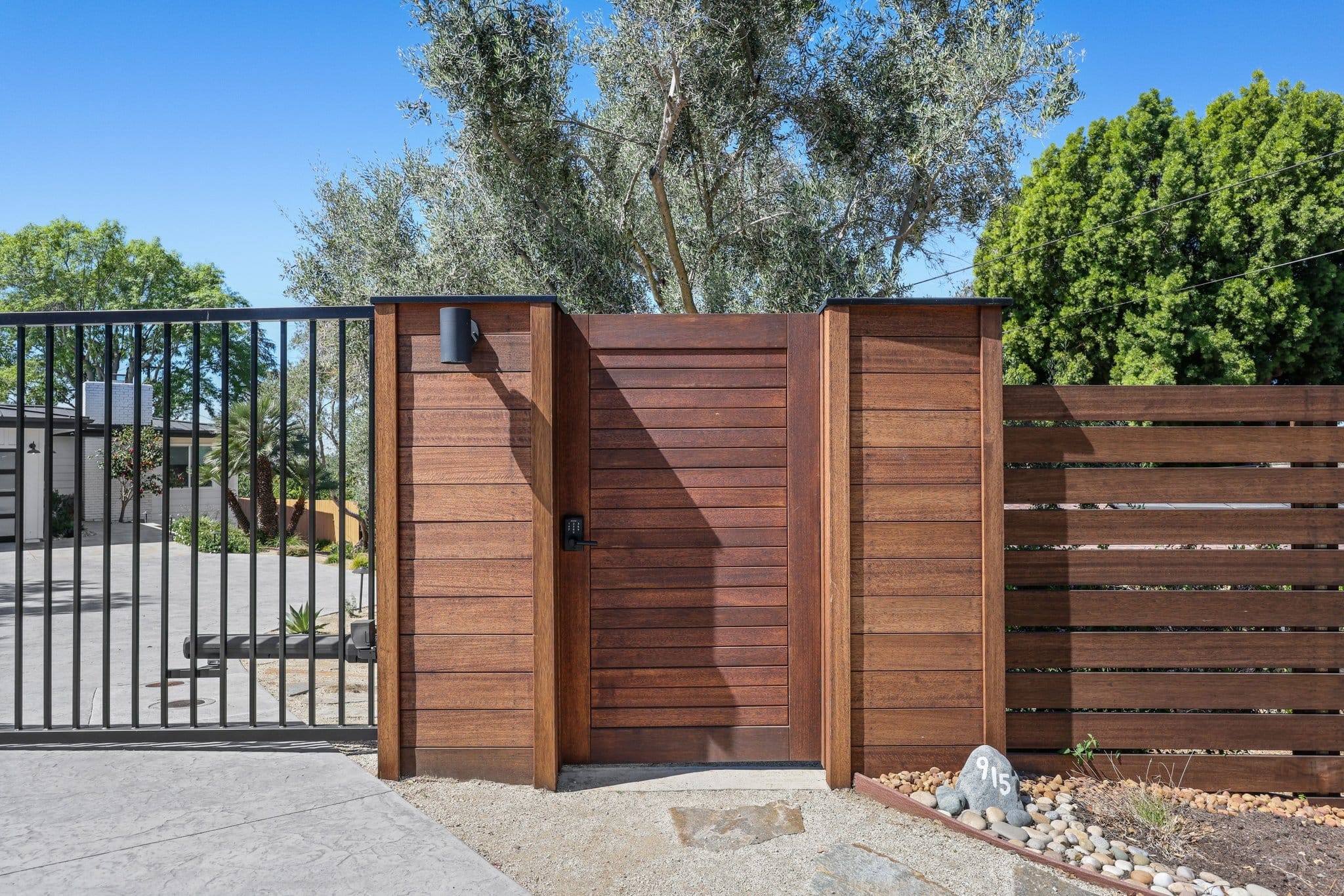 Modern horizontal-slat ipe wood entry gate and fence with concrete driveway