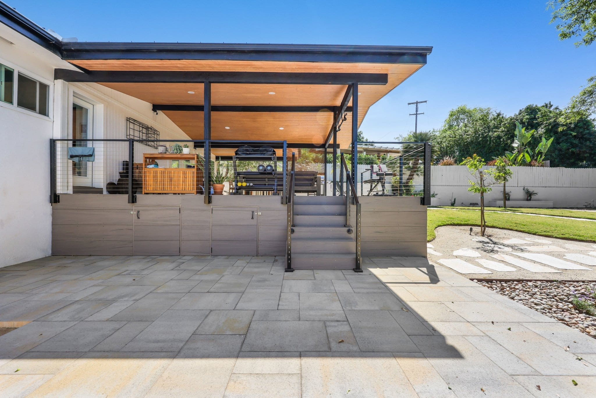 covered patio deck with wood ceiling, cable railing and stone pavers