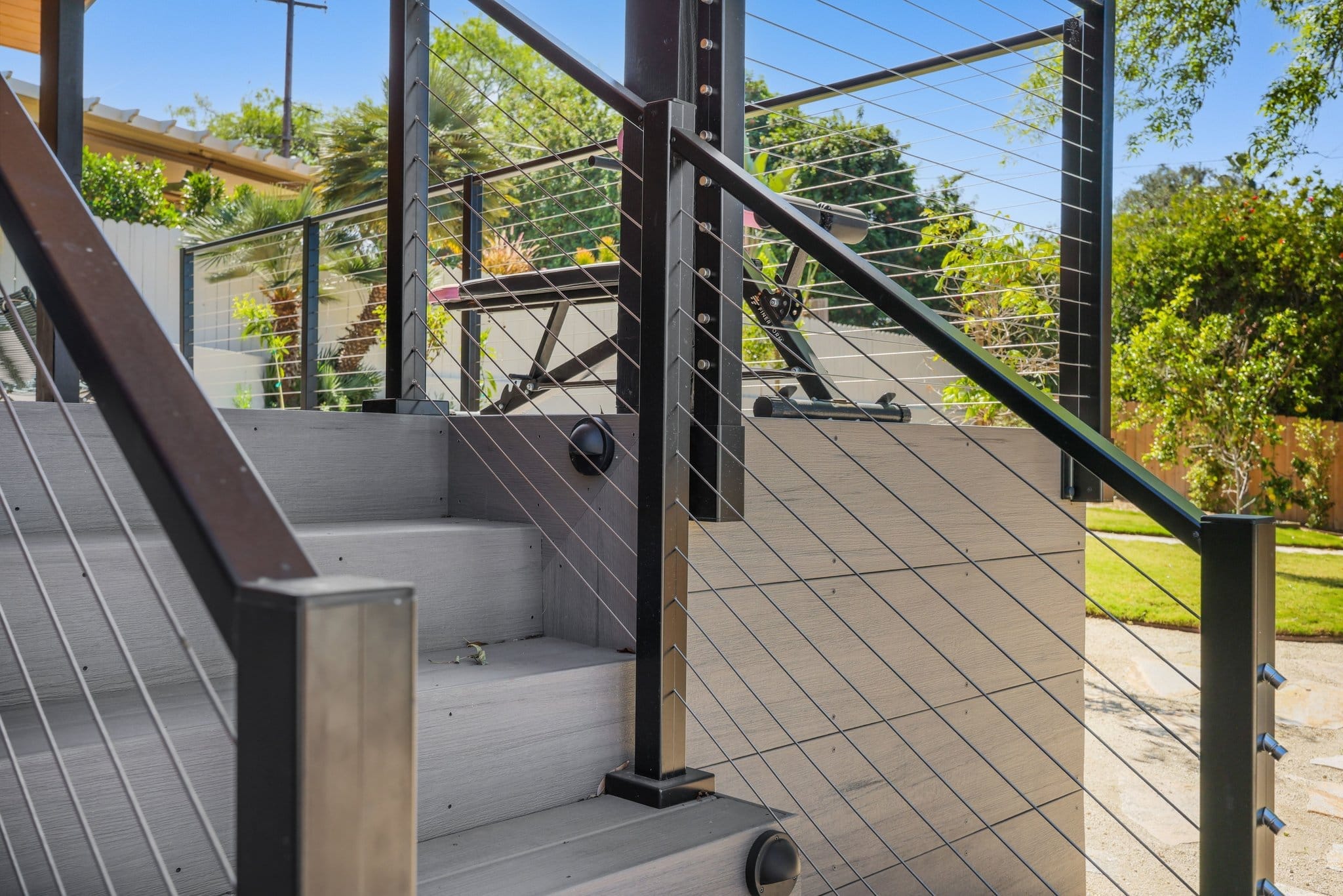 composite deck stairs with steel cable railing leading to backyard patio