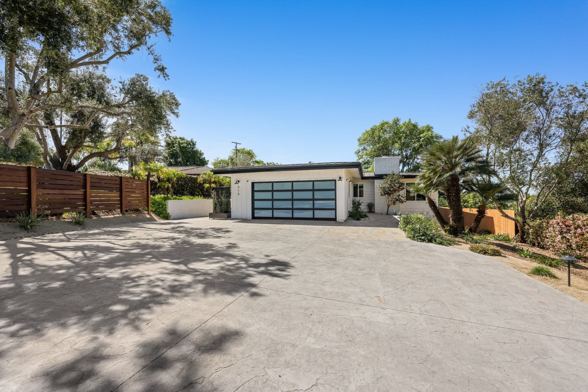 Midcentury ranch home exterior with glass garage door and stamped concrete driveway