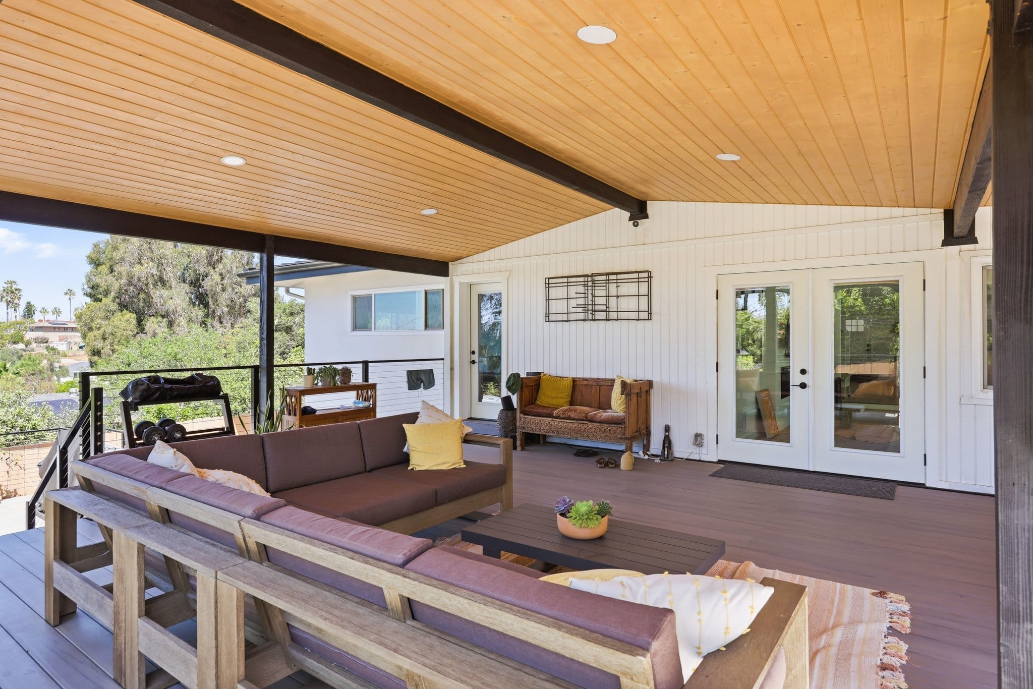 Covered deck with tongue-and-groove wood ceiling, sectional sofa and French doors
