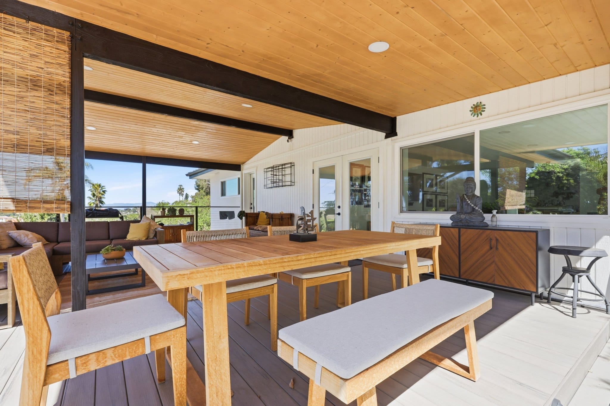 Outdoor deck dining area with teak table, bench seating and walnut sideboard