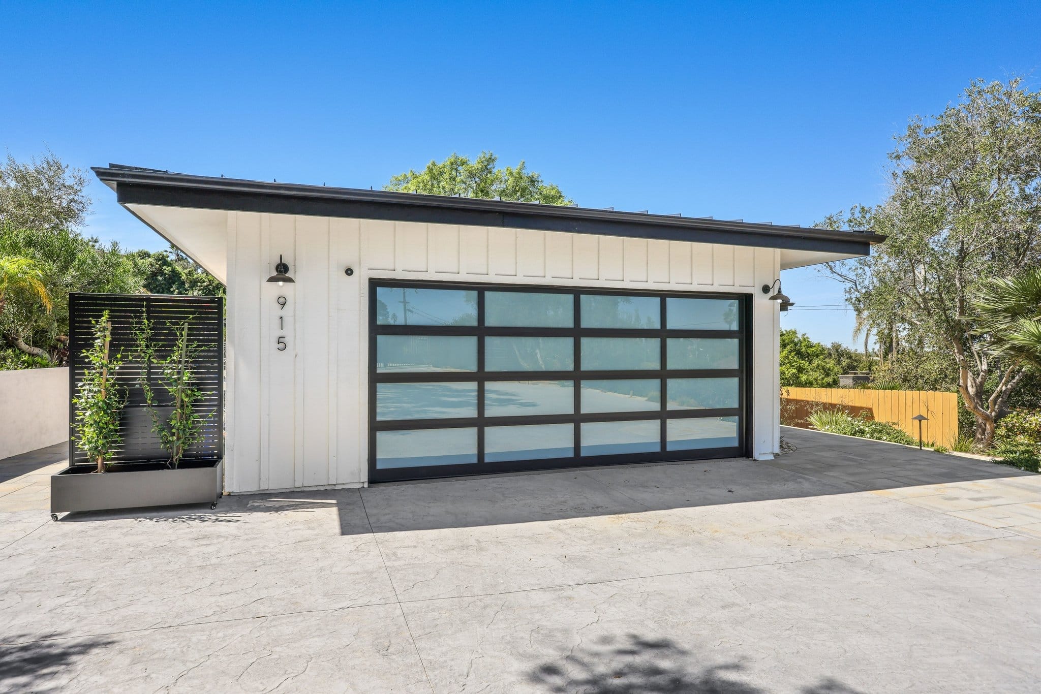 White board-and-batten garage with frosted-glass door and angled butterfly roofline