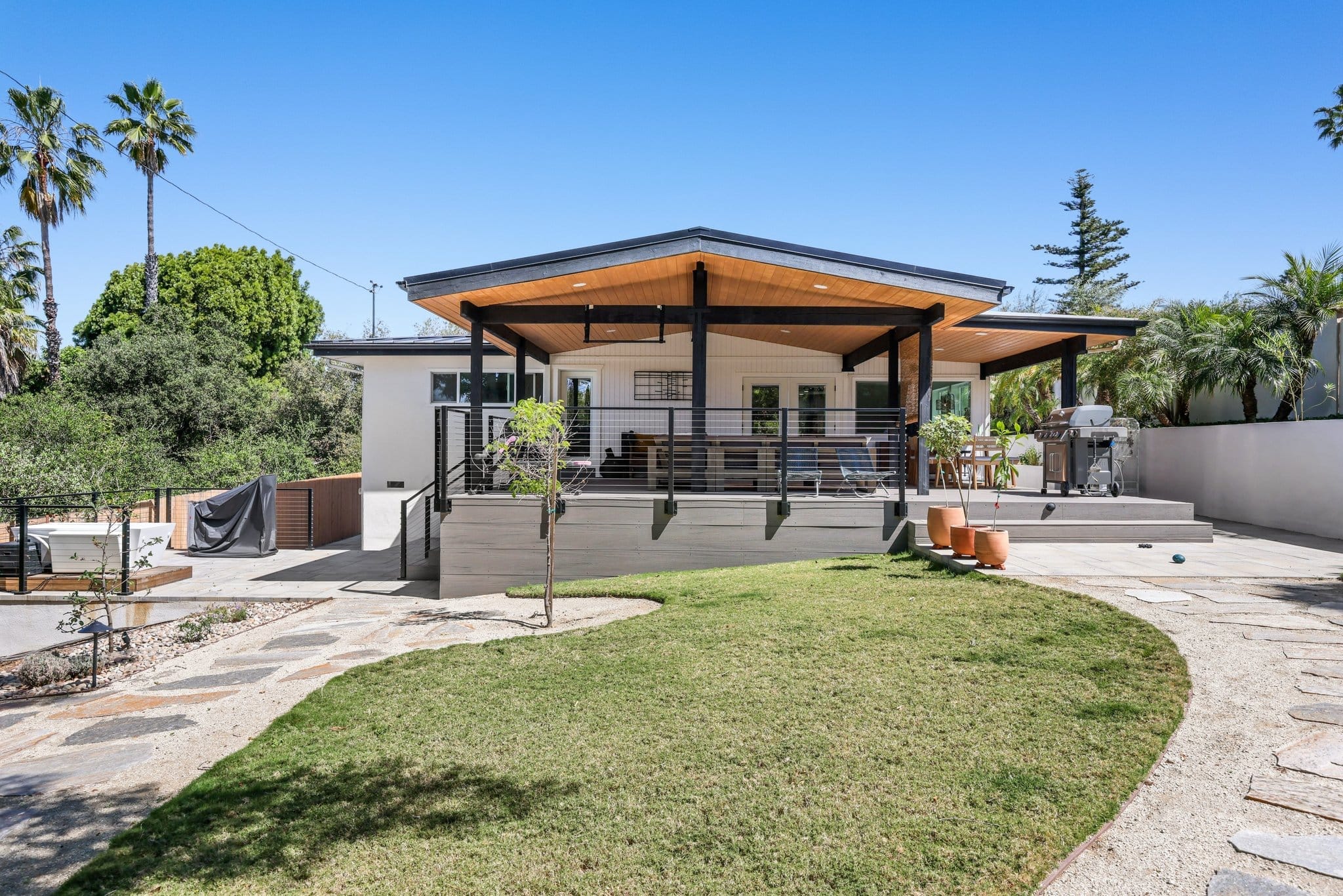 backyard covered patio with wood-clad ceiling and cable-railed composite deck