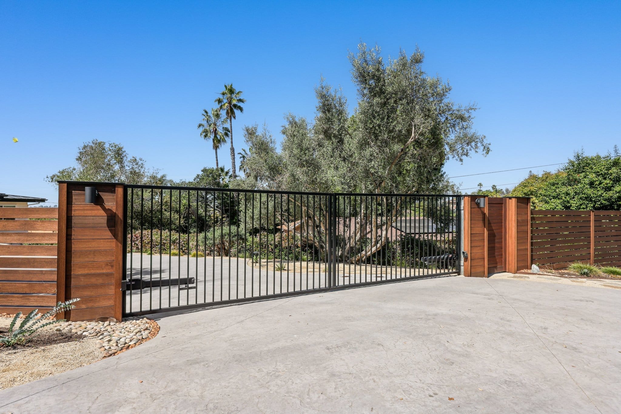 Stained concrete driveway with horizontal wood-slat fencing and modern black metal gate