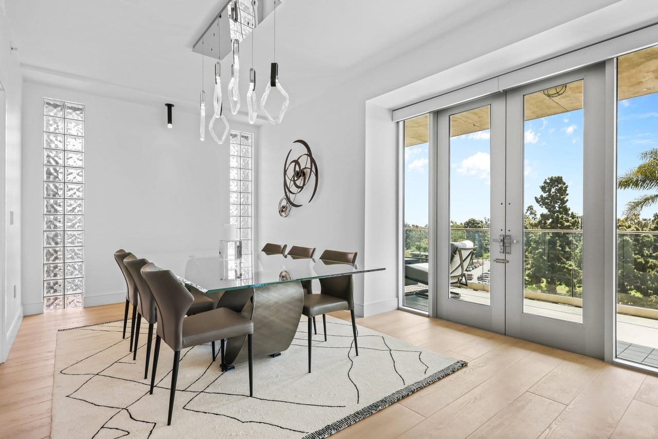 Bright dining area with glass table, leather chairs, glass-block windows and balcony doors