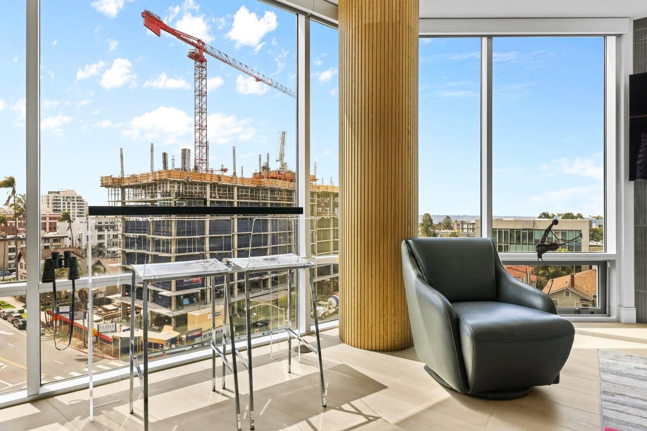 High-rise sitting nook with leather swivel chair facing floor-to-ceiling city-view windows