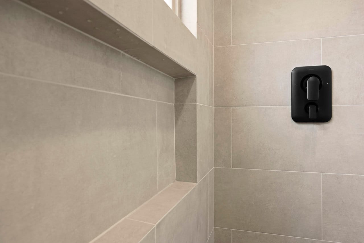 close-up of greige shower tile with built-in niche and black controls