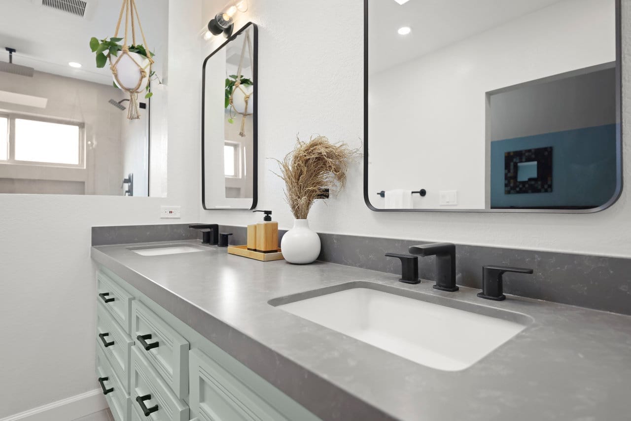 Modern bathroom vanity with gray quartz counter, black faucets, and undermount sinks