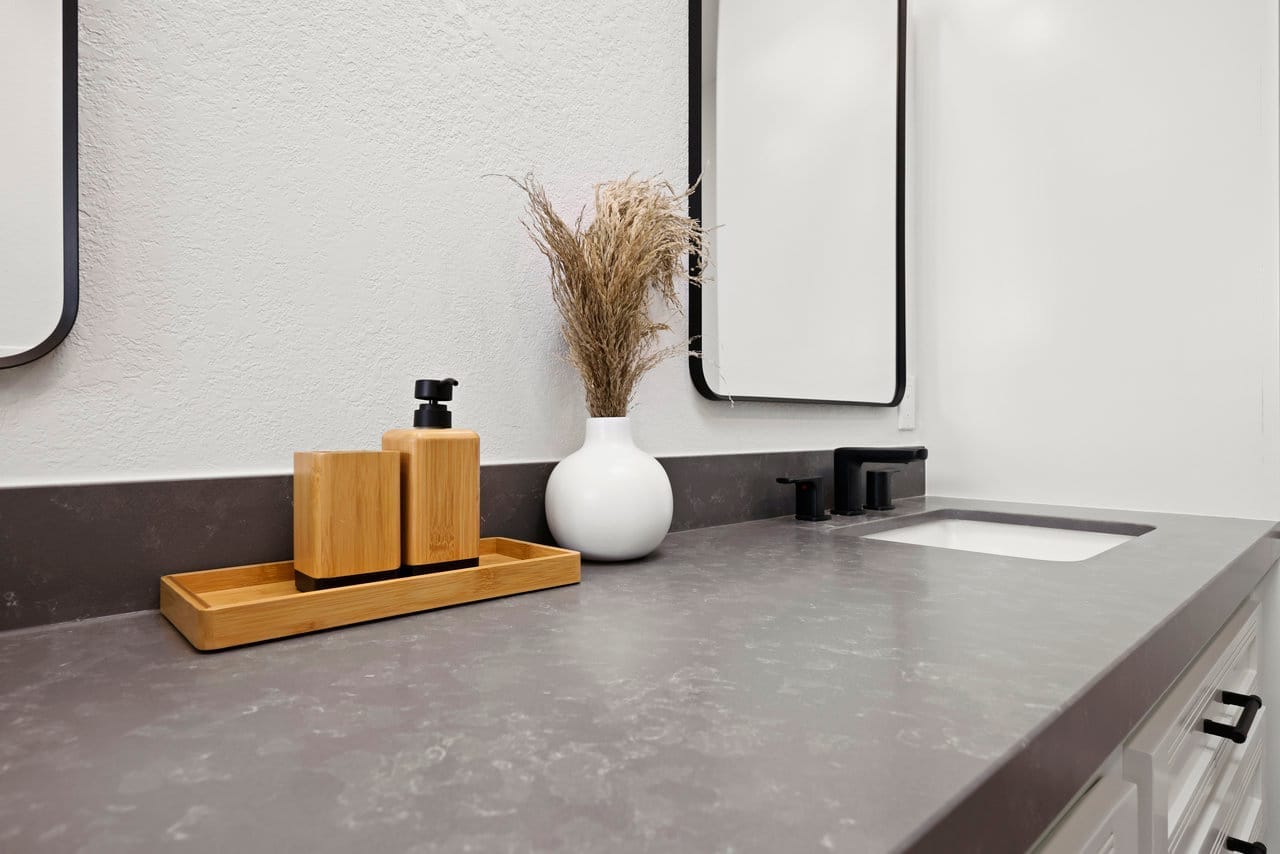 Gray quartz vanity counter styled with bamboo tray and pampas grass in vase
