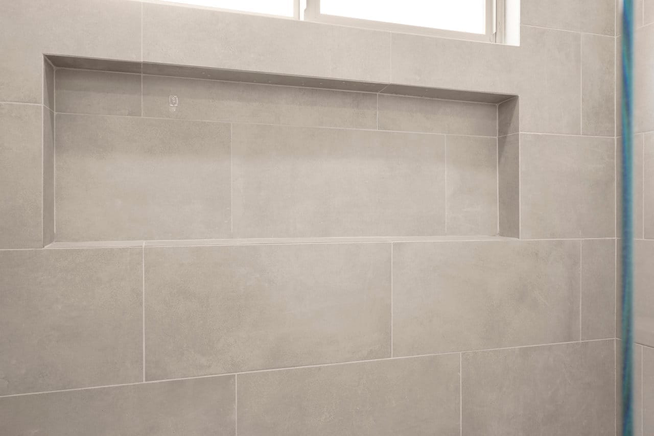 Recessed shower niche set in large-format gray porcelain wall tile