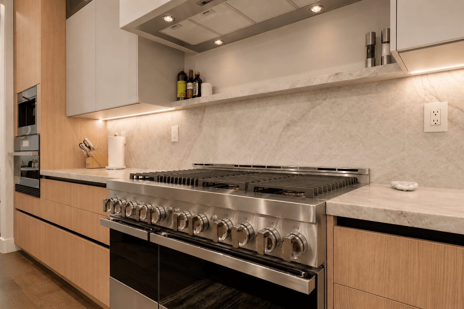 Contemporary kitchen featuring stainless gas range and marble slab backsplash
