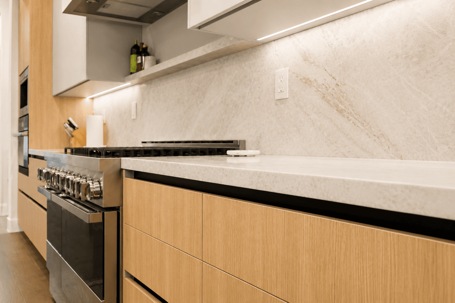 Galley kitchen with oak cabinets, quartz counters and stainless gas range