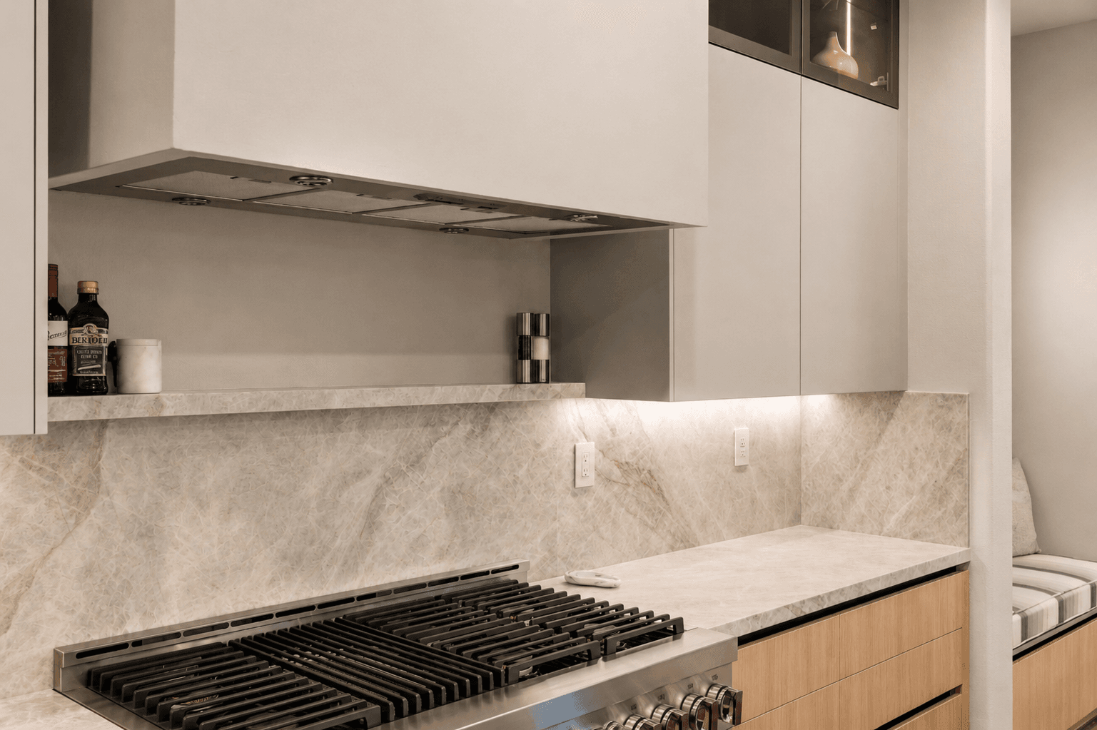 Sleek kitchen with stainless range hood, gas cooktop and marble backsplash