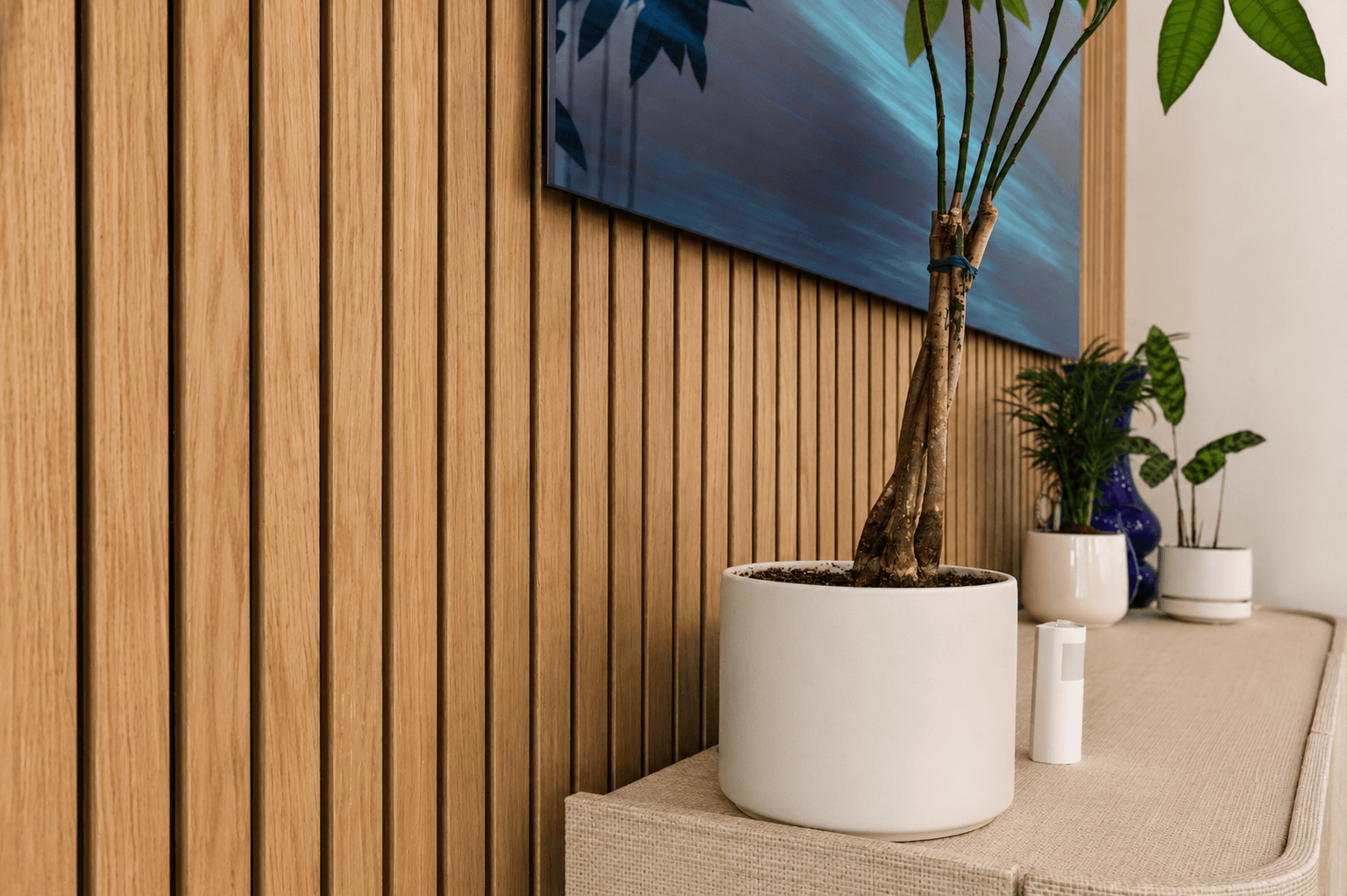 Wood-slat accent wall with potted greenery and blue abstract artwork in modern living space
