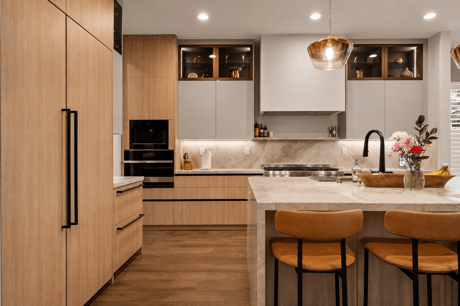 Modern kitchen with light wood cabinetry, stone backsplash and glass-front upper cabinets