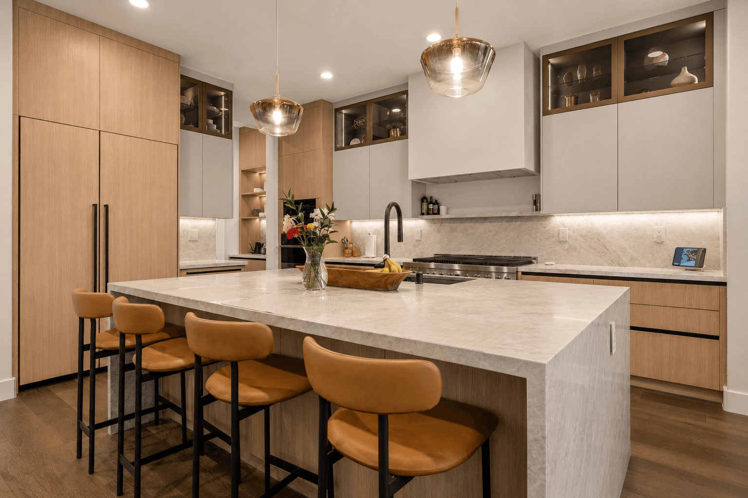 Contemporary kitchen island with quartz countertop, tan leather stools and pendant lighting