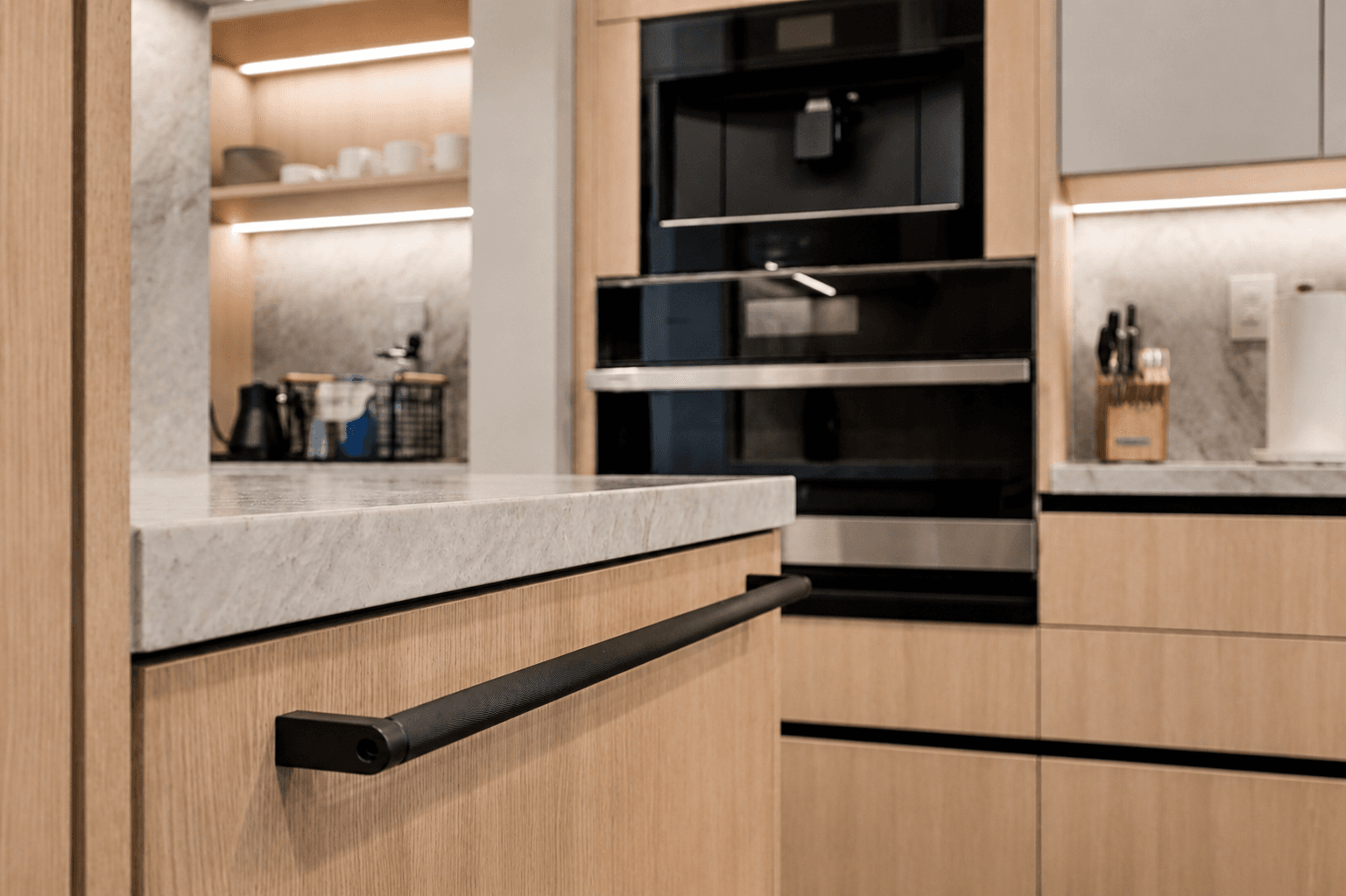 Light oak kitchen drawer with black bar pulls and marble countertop detail