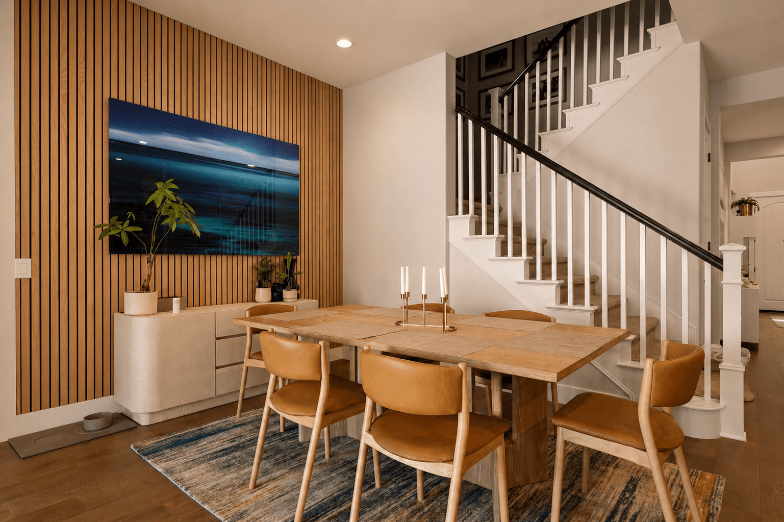 Dining area with slatted wood accent wall, oak table and staircase