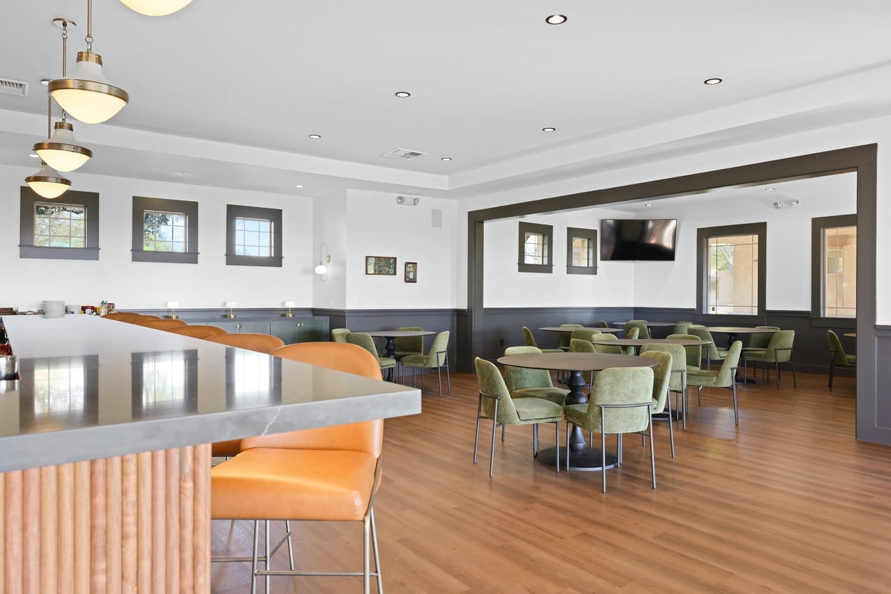 clubhouse dining area with wood floors, round tables, and green upholstered chairs