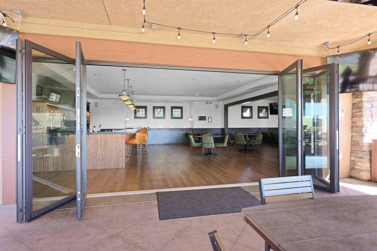 folding glass walls opening a wood-floored lounge bar onto a stone patio