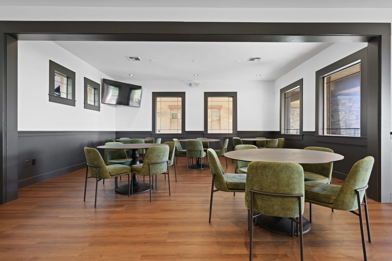 Open dining room featuring green upholstered seating, dark wainscoting and a wide framed opening
