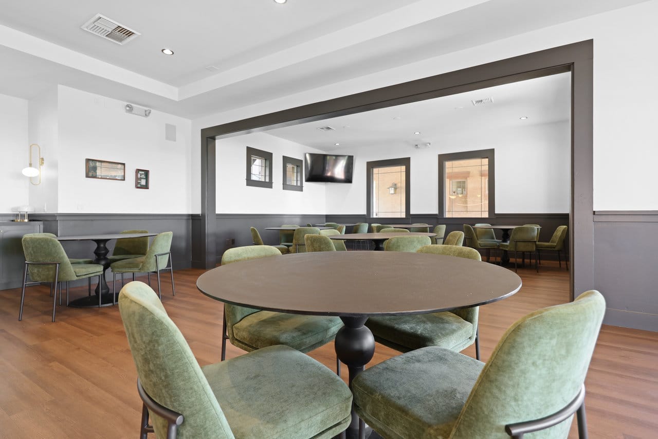 Two-room dining space with round tables, sage velvet chairs and gray trim accents
