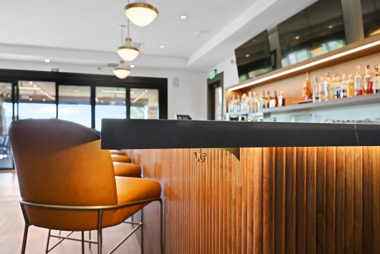 Close view of bar counter edge with tan leather seating and ribbed wood paneling