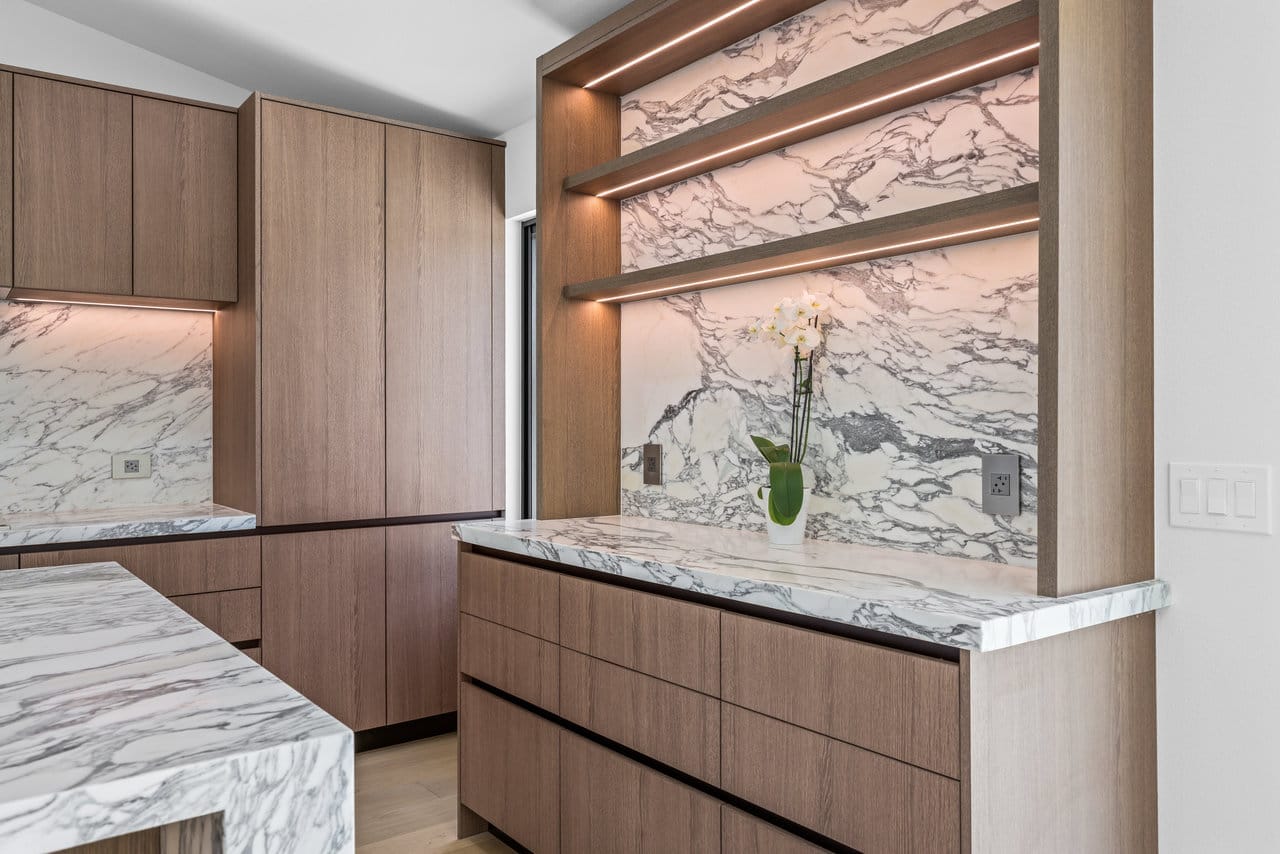 Kitchen detail with backlit marble shelf niche, oak cabinets, and orchid centerpiece