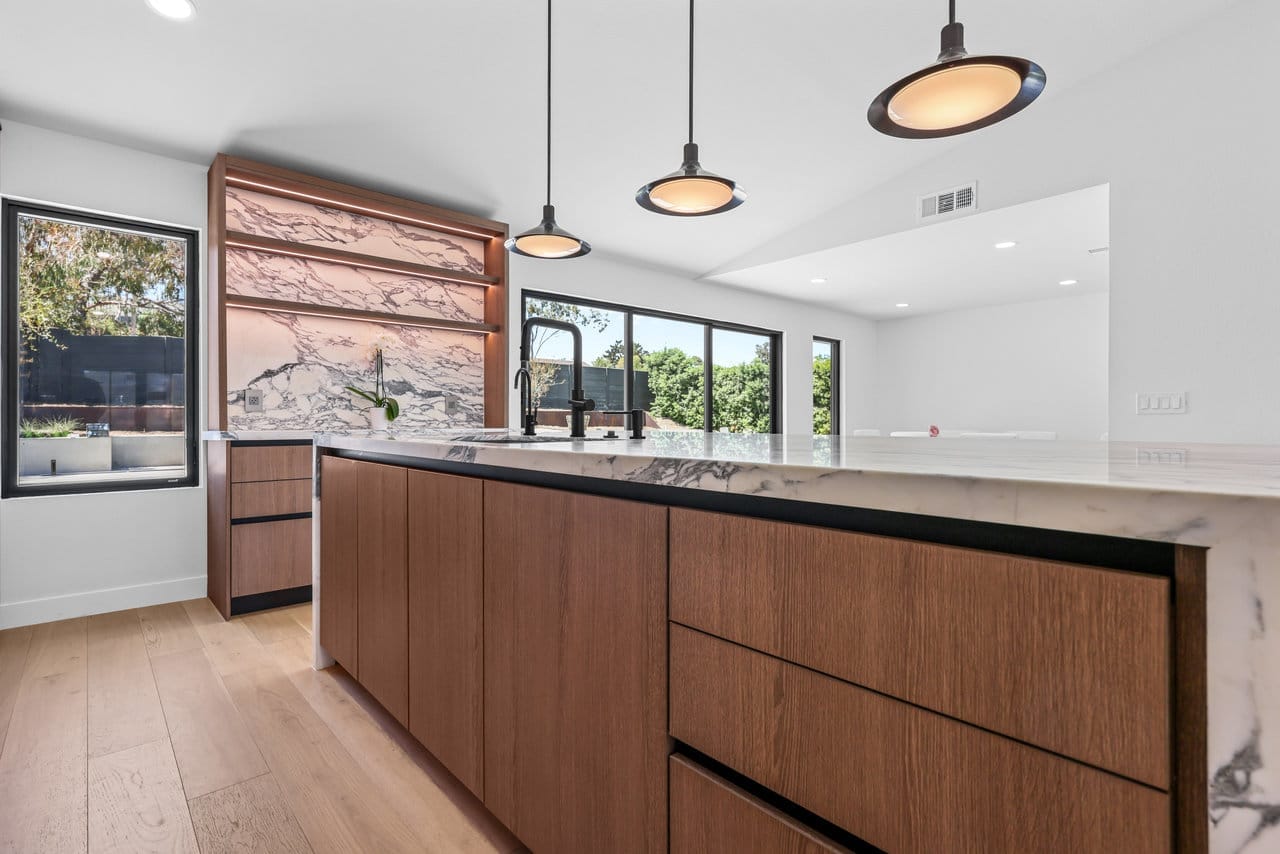 Modern kitchen with walnut island, white marble waterfall counter and copper-framed backsplash