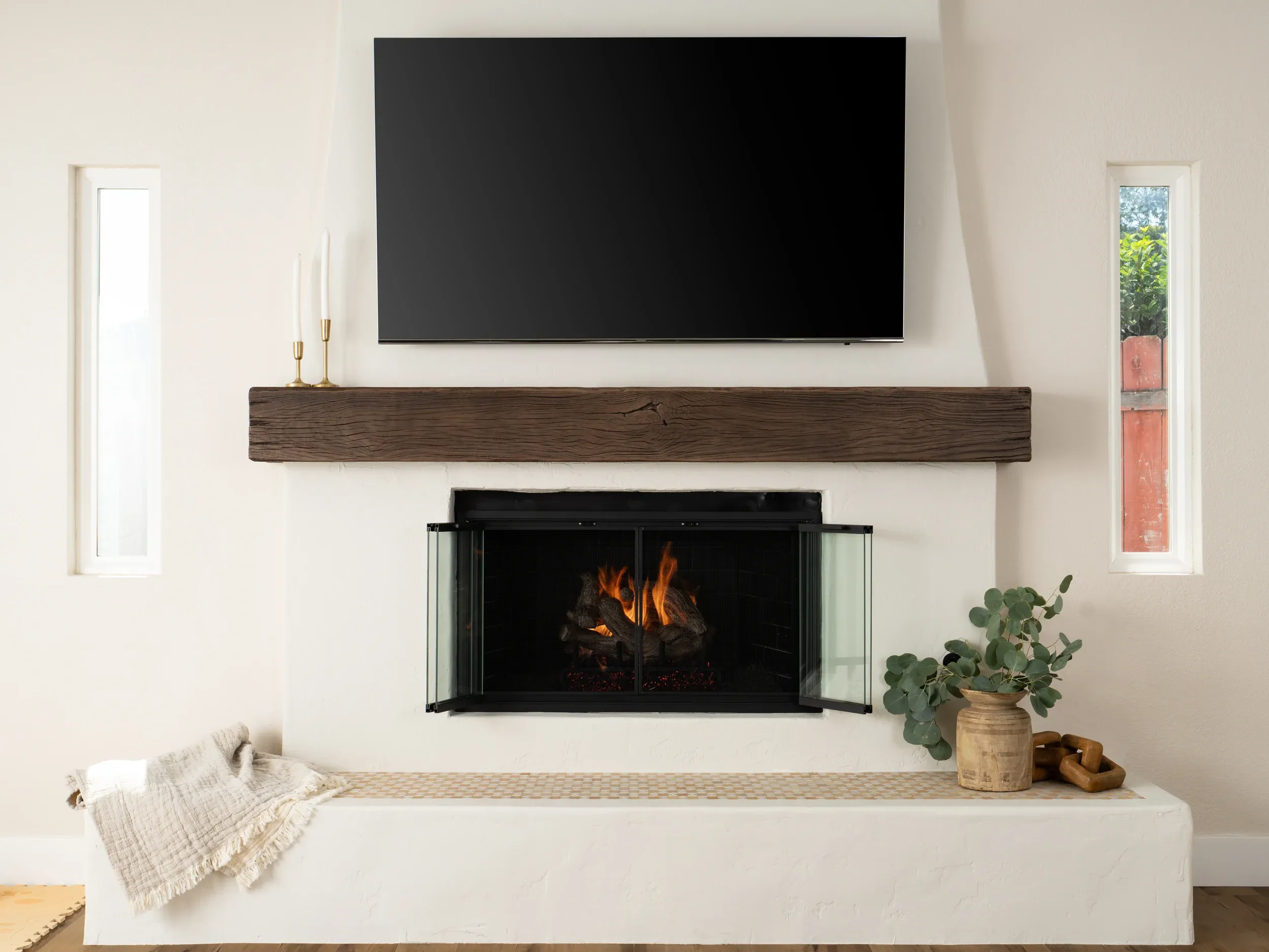Living room with white plaster fireplace, reclaimed wood mantel and mounted television