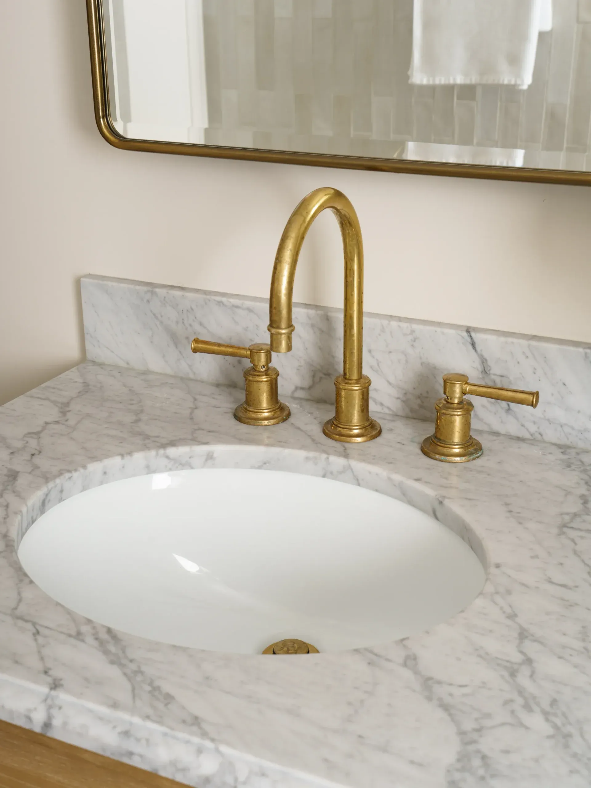 Close-up of brass widespread faucet on veined marble vanity with undermount sink