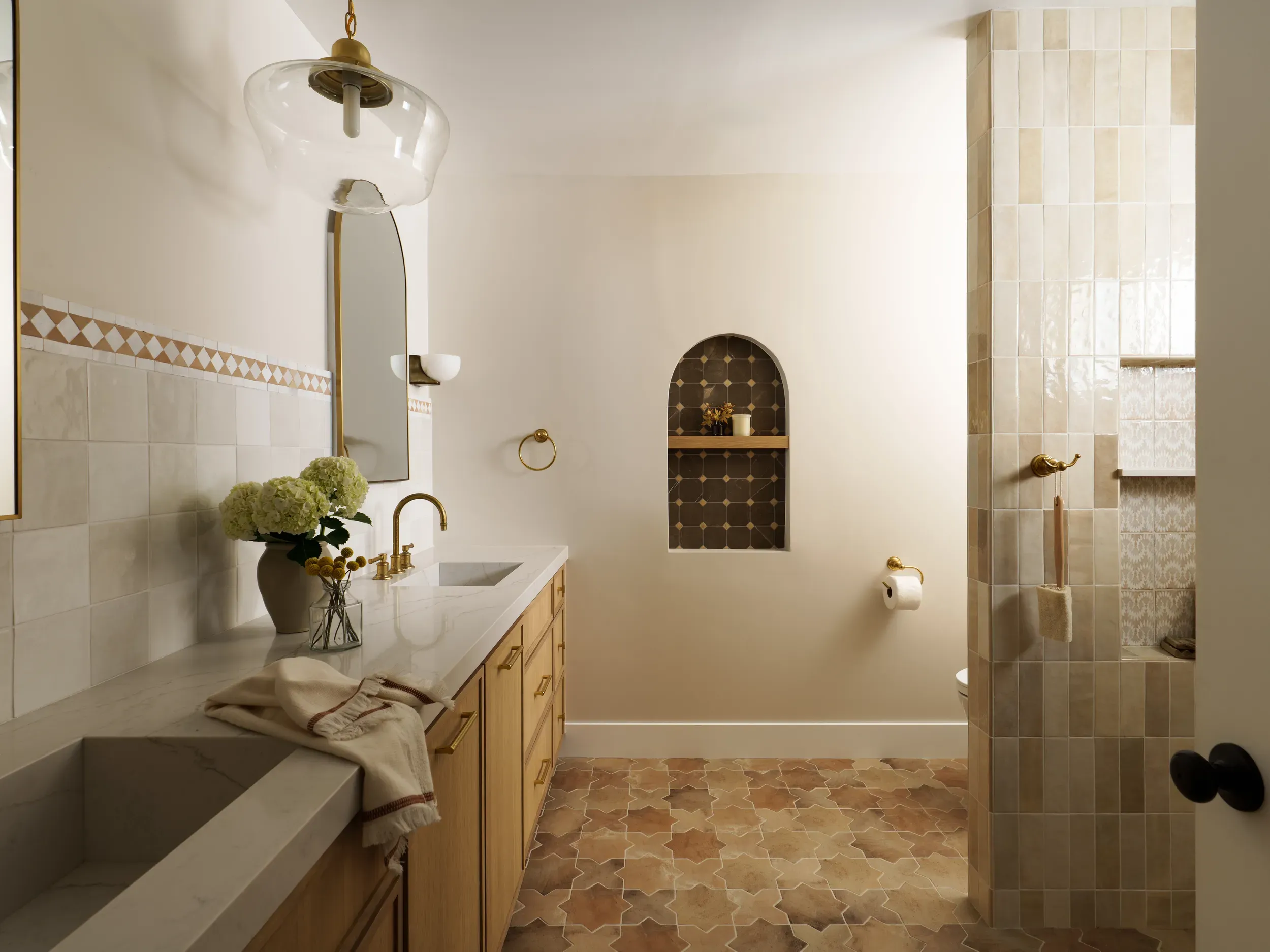 Spanish-style bathroom with arched tile niche, terracotta floor and wood vanity