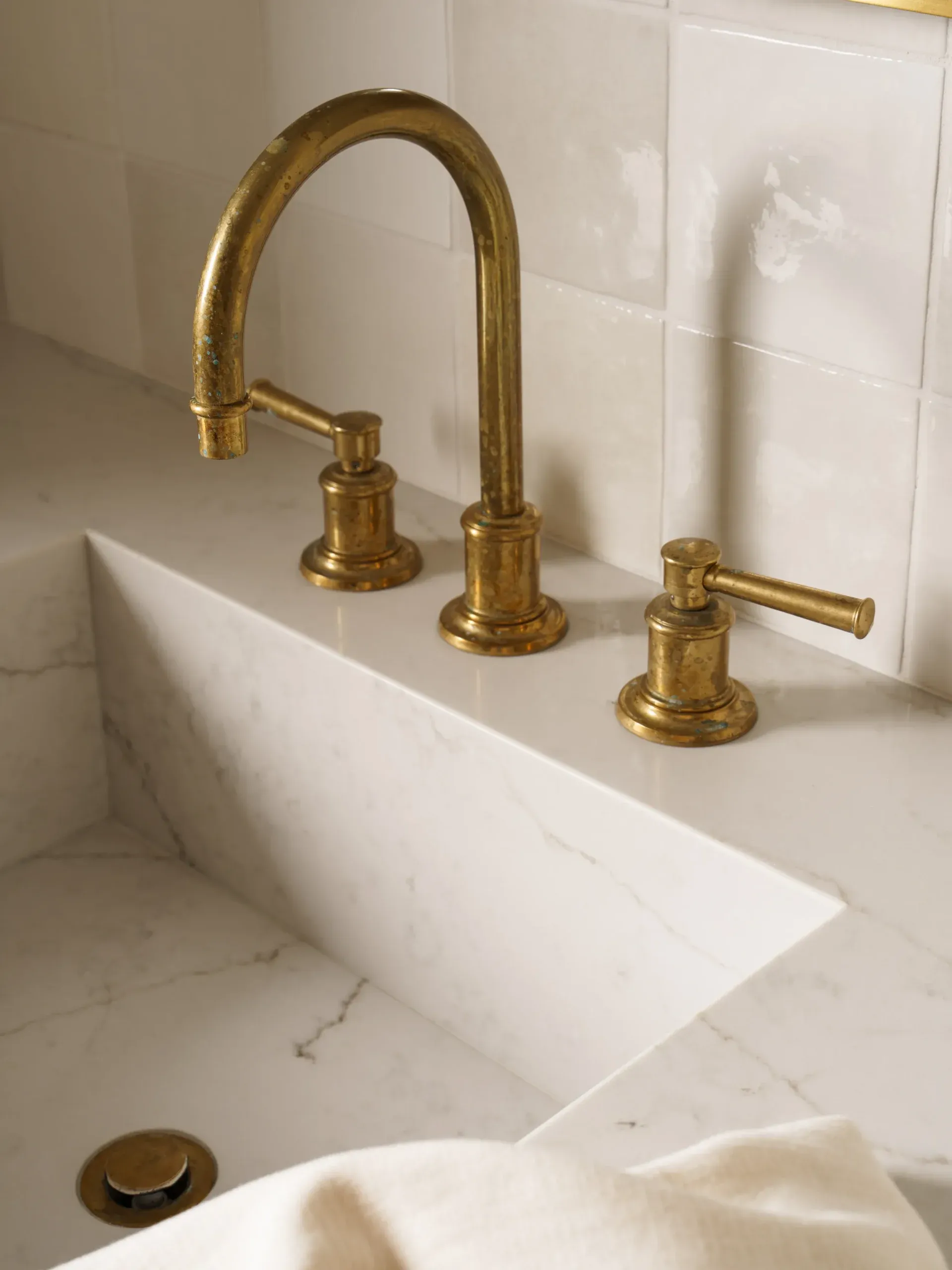 Close-up of brushed brass widespread faucet on white marble bathroom sink