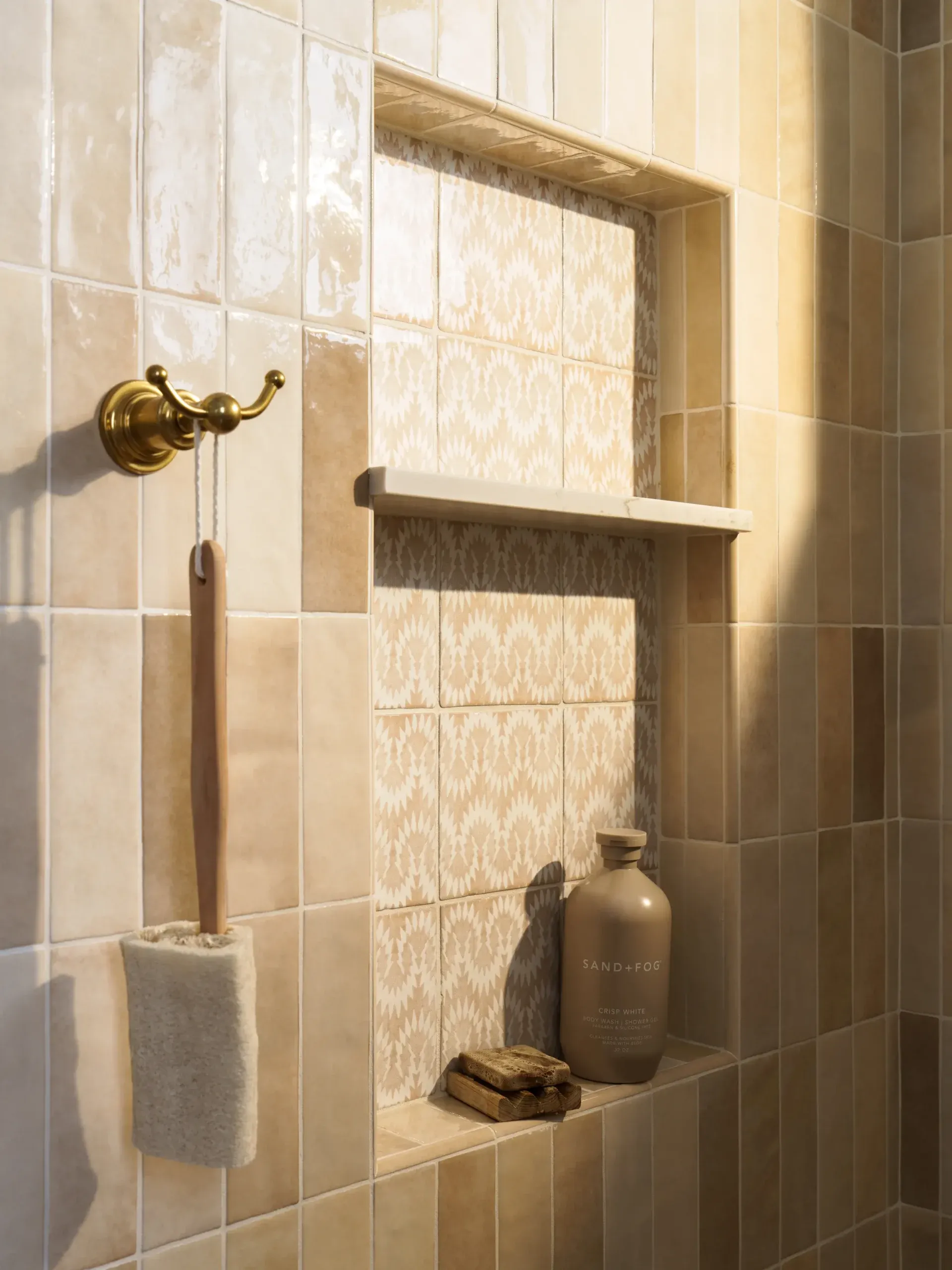 Shower niche framed in handmade tile with brass hook and ceramic vessel