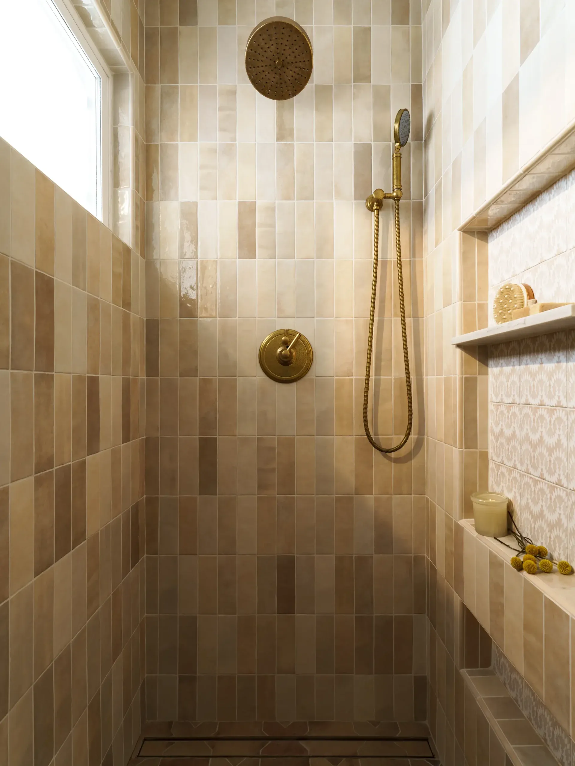 Walk-in shower clad in earthy zellige tile with brass rainfall and handheld fixtures
