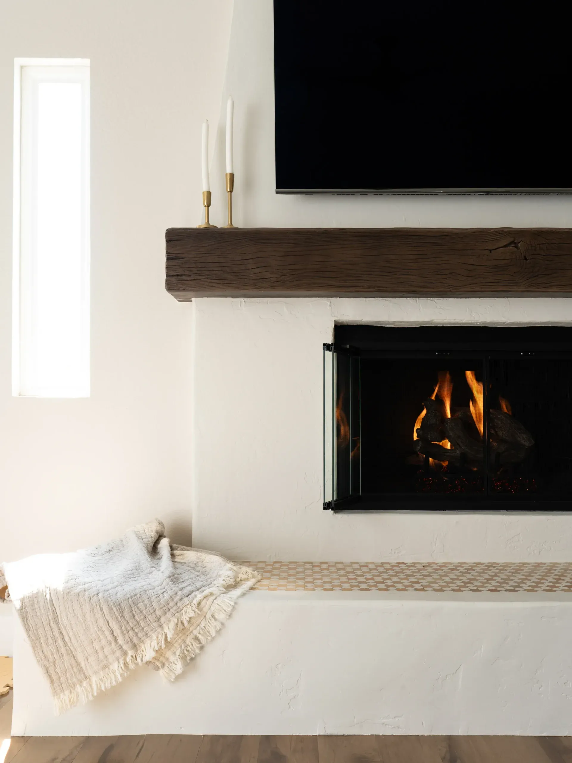 Minimalist white fireplace with reclaimed wood mantel and built-in bench