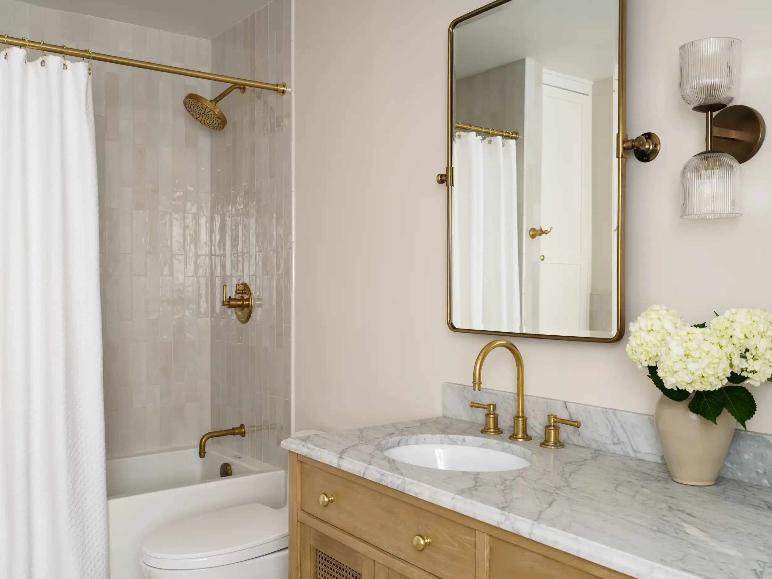 Transitional bathroom with marble shower-tub surround and brass fixtures