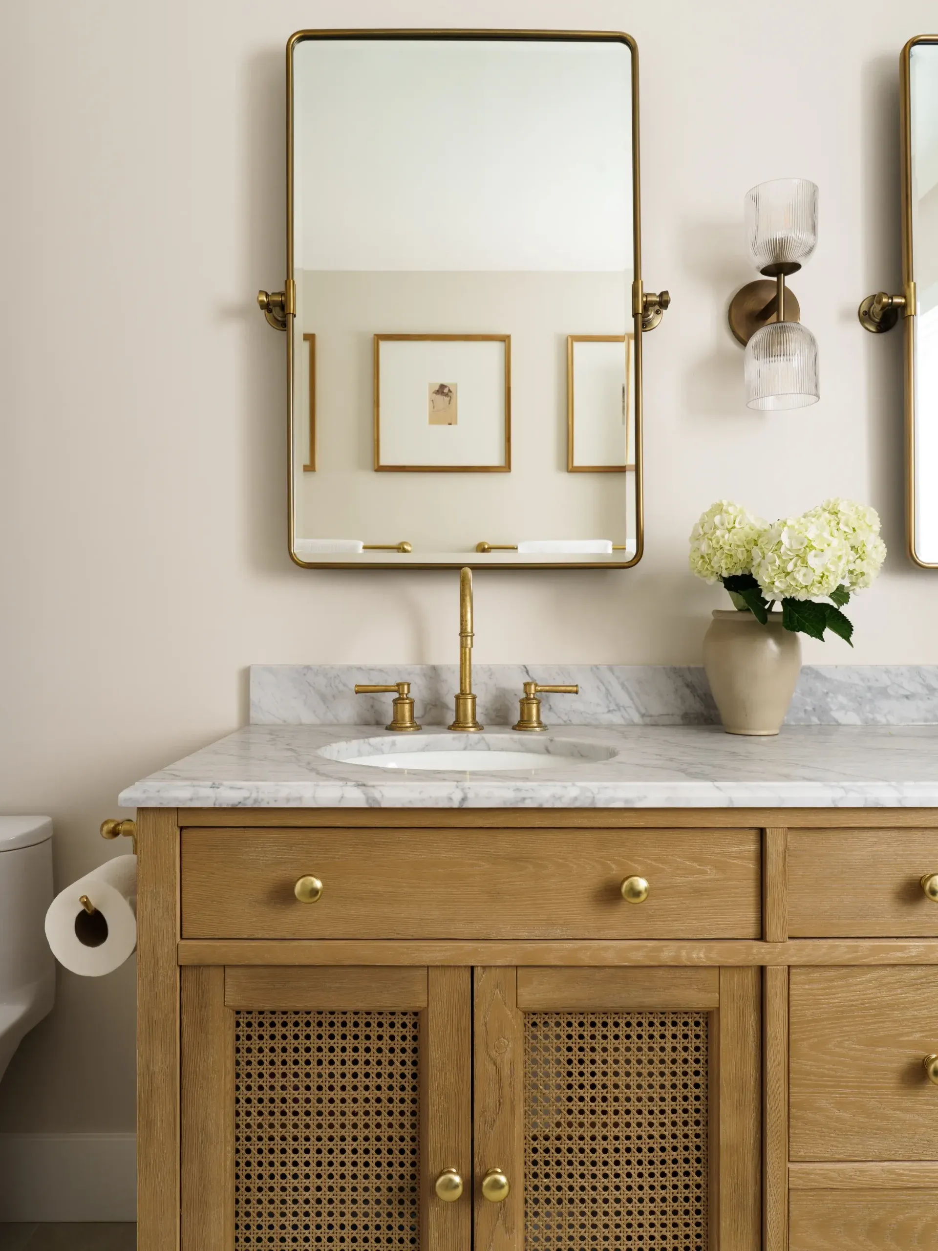 Powder bath vanity with oak cane cabinet, marble counter and brass fixtures