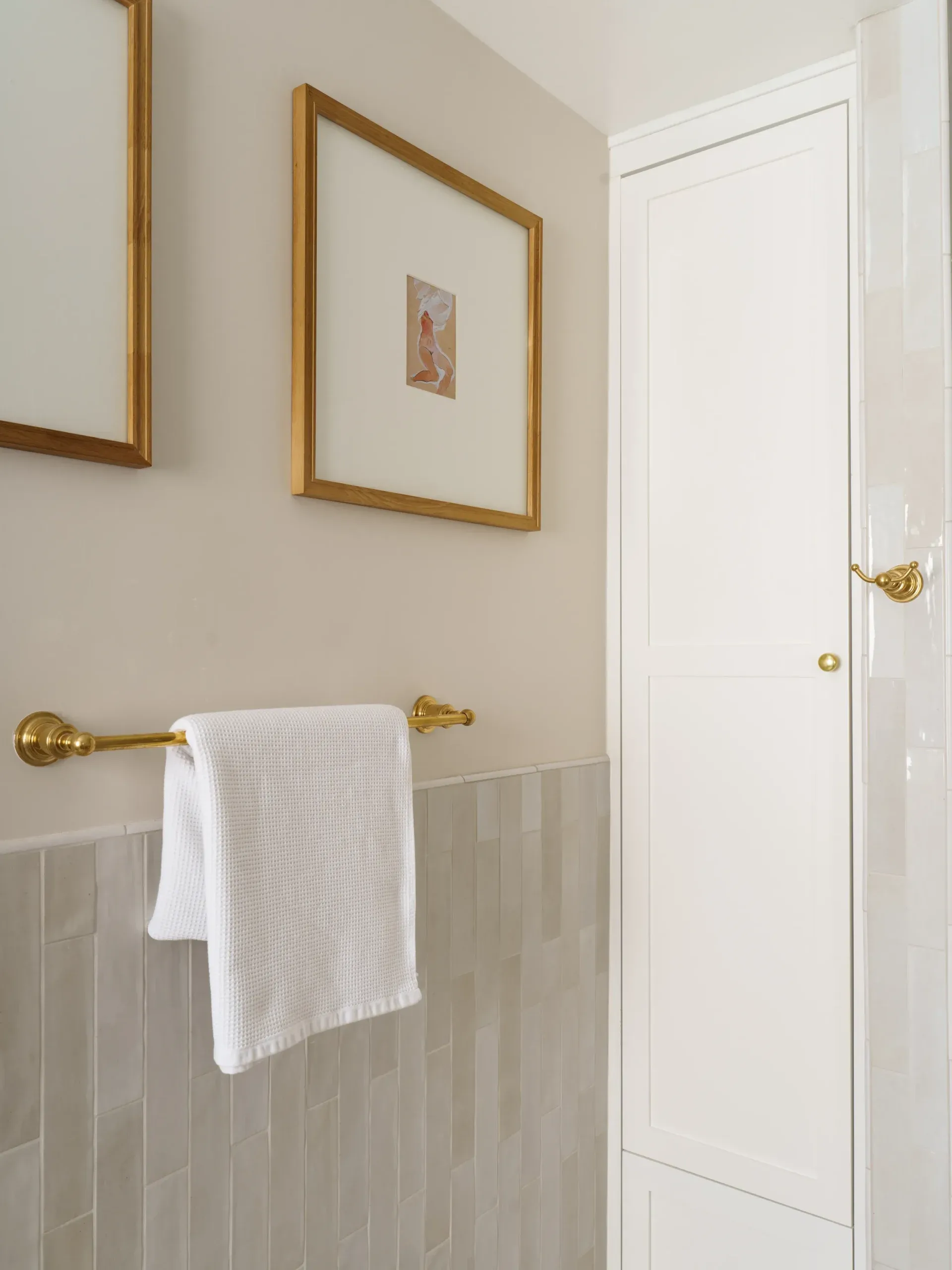 Neutral bathroom with vertical zellige wainscot, gilded towel bar and framed art