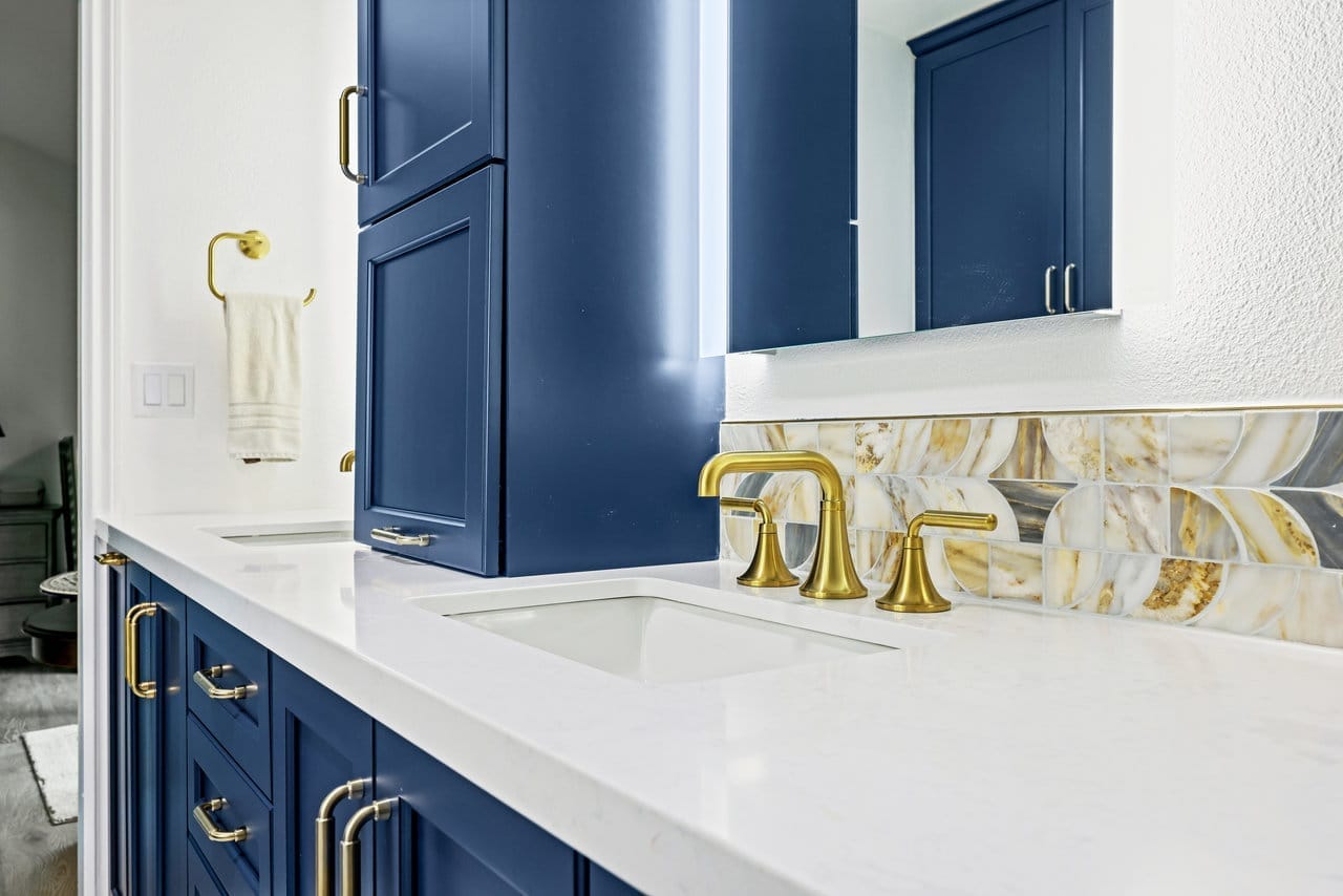 angled view of navy bathroom vanity with quartz top and warm glass tile backsplash