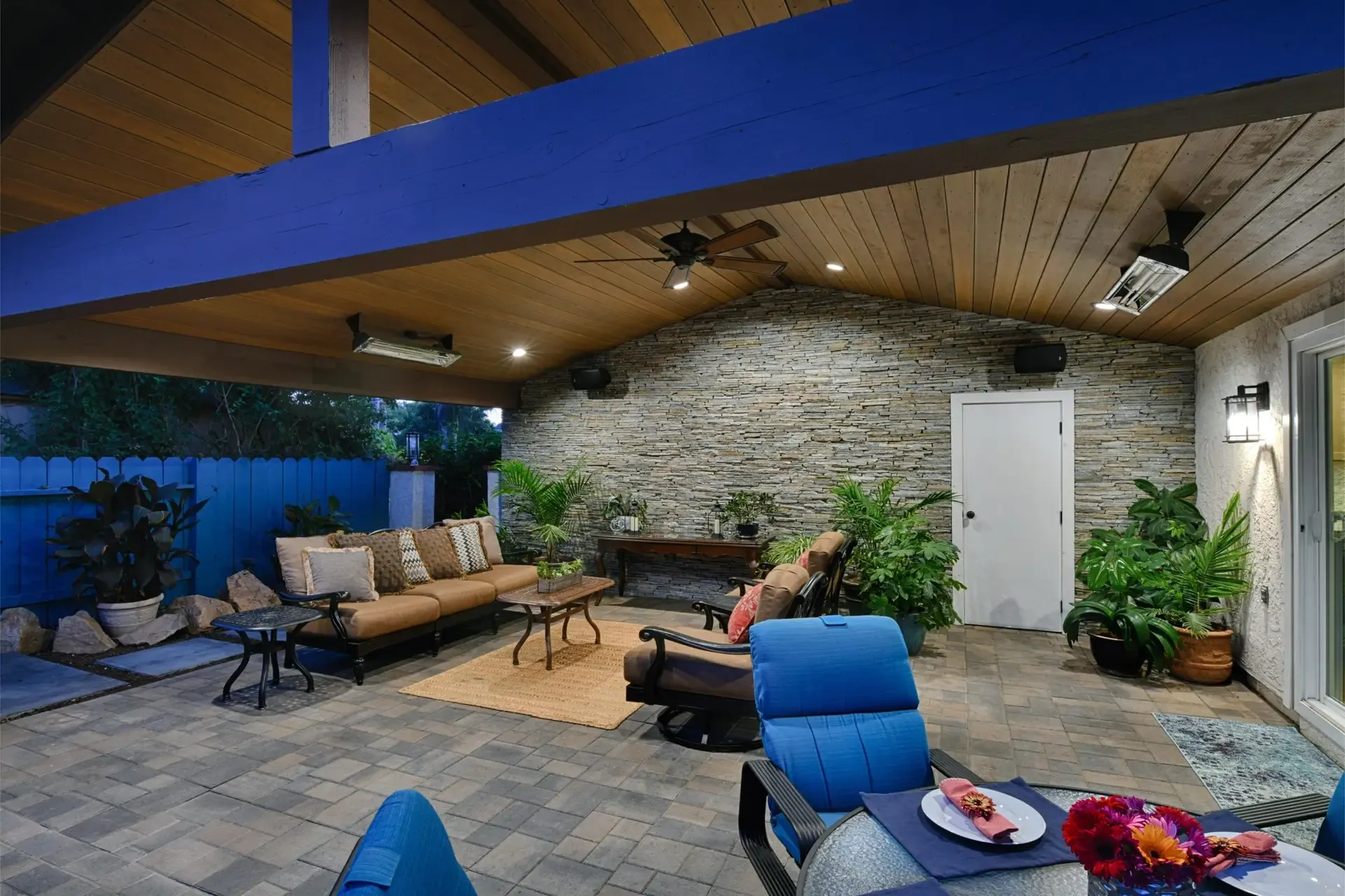 Backyard covered patio featuring stacked stone wall and blue painted beam ceiling