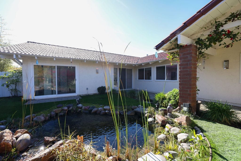 Backyard exterior with tile-roof home, koi pond and ornamental grasses