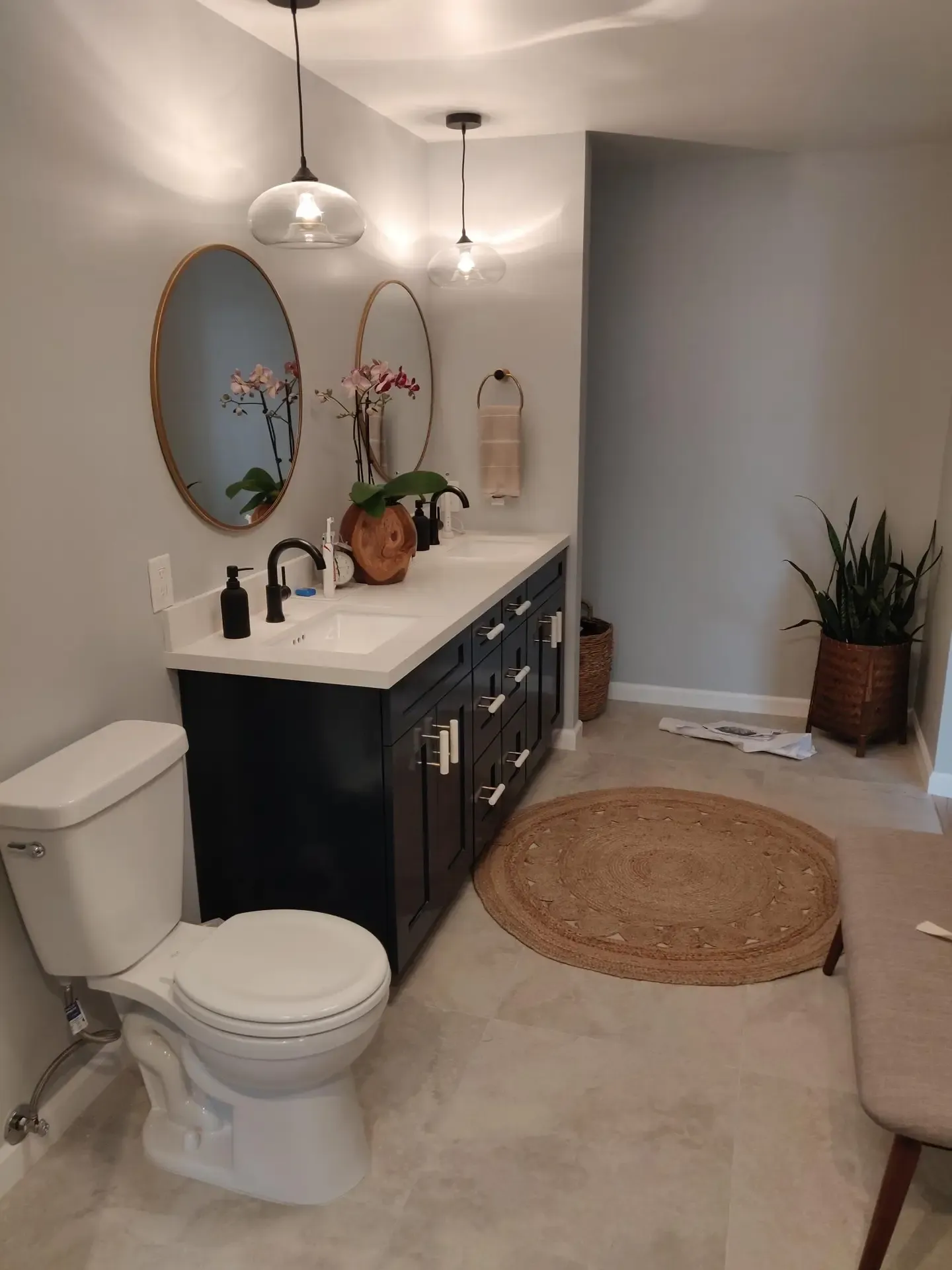 Bathroom vanity in dark cabinetry with dual round mirrors and pendant lighting