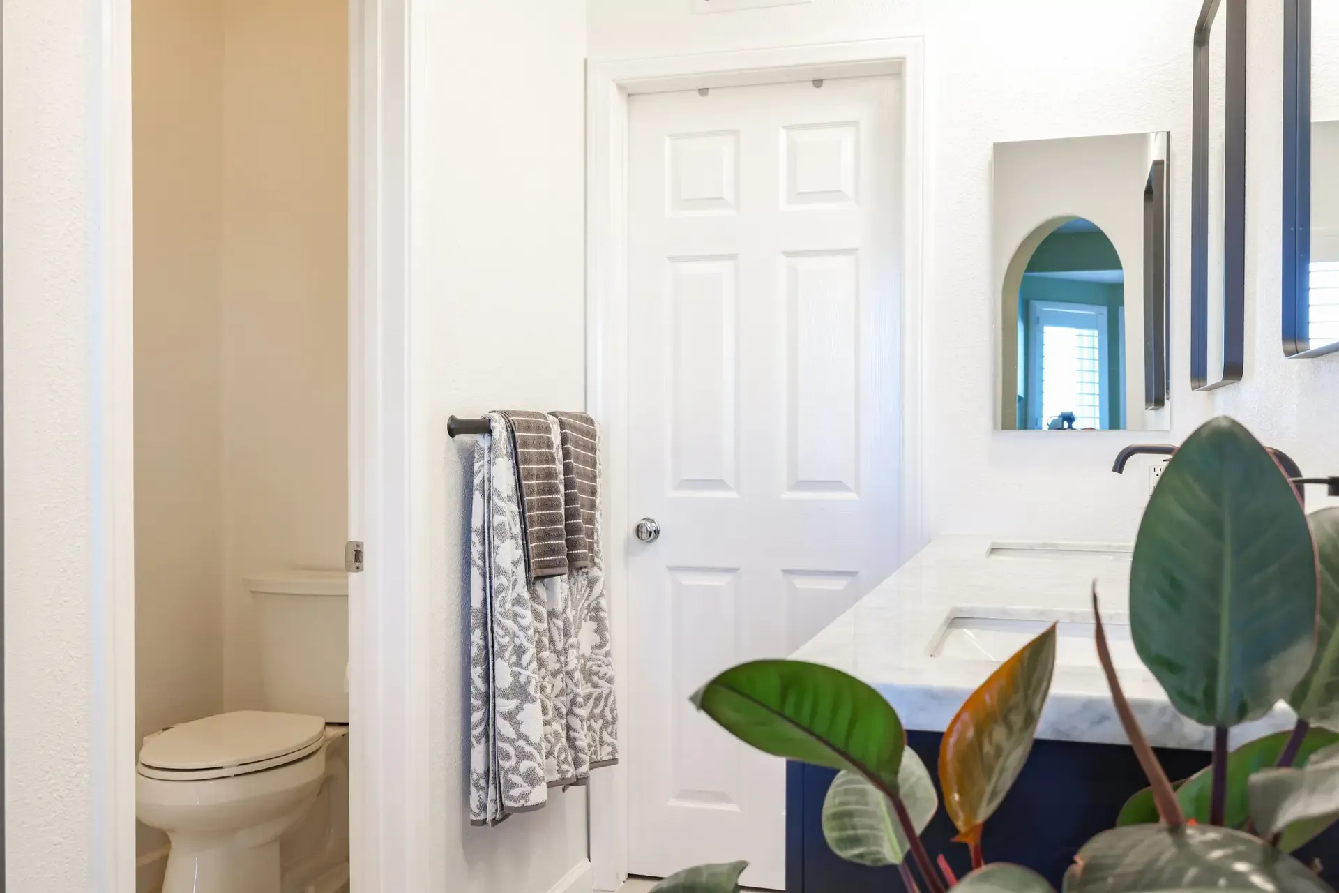 Bathroom with navy vanity, marble top, separate toilet room, and towel bar