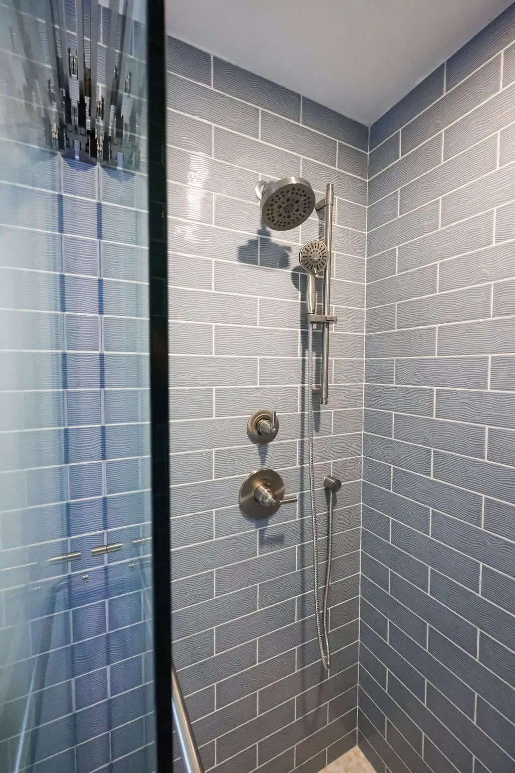 Blue glass-tiled shower with chrome rainfall head and sliding bar fixture