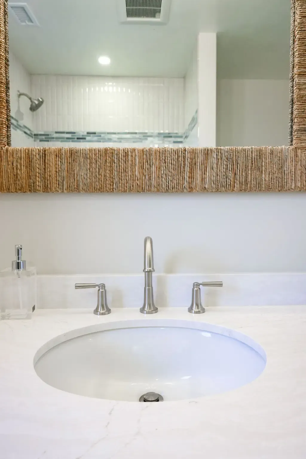 Bright bathroom vanity with undermount sink, chrome faucet and rope-trimmed mirror