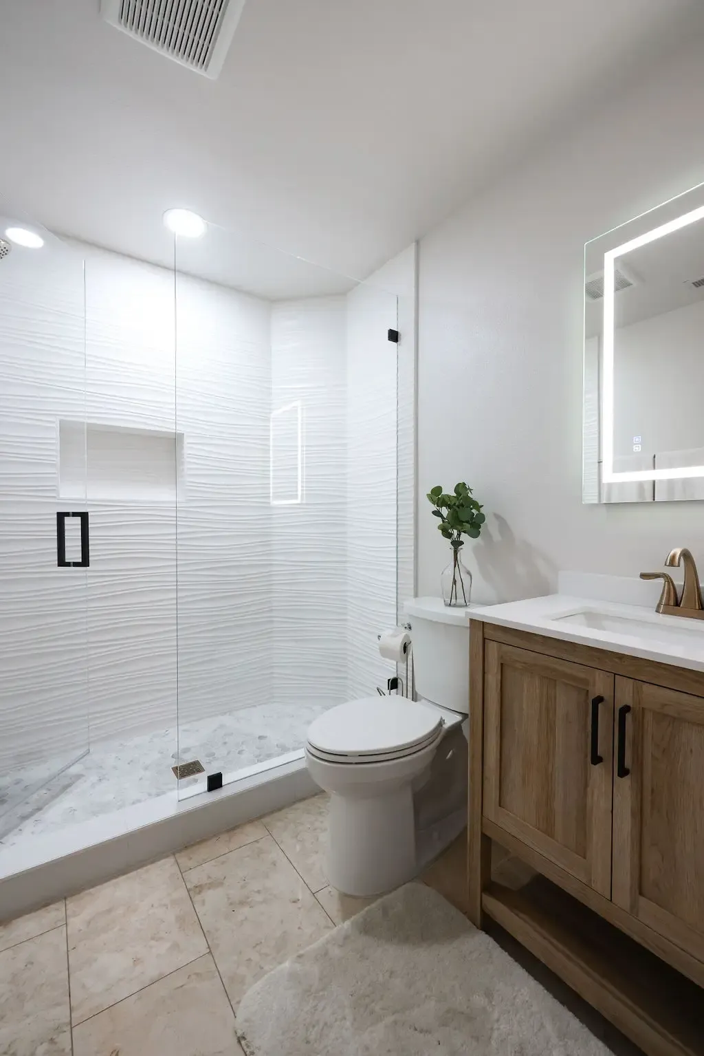 Bright bathroom with glass walk-in shower, white subway tile and oak vanity