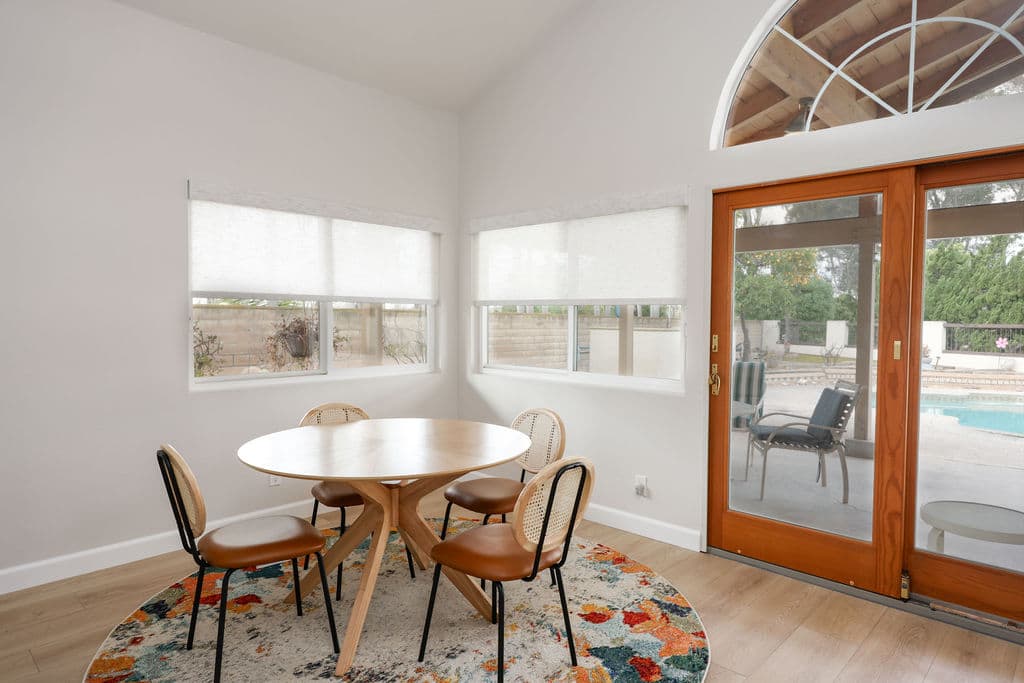 Bright breakfast nook with round white table, woven chairs and patio French doors