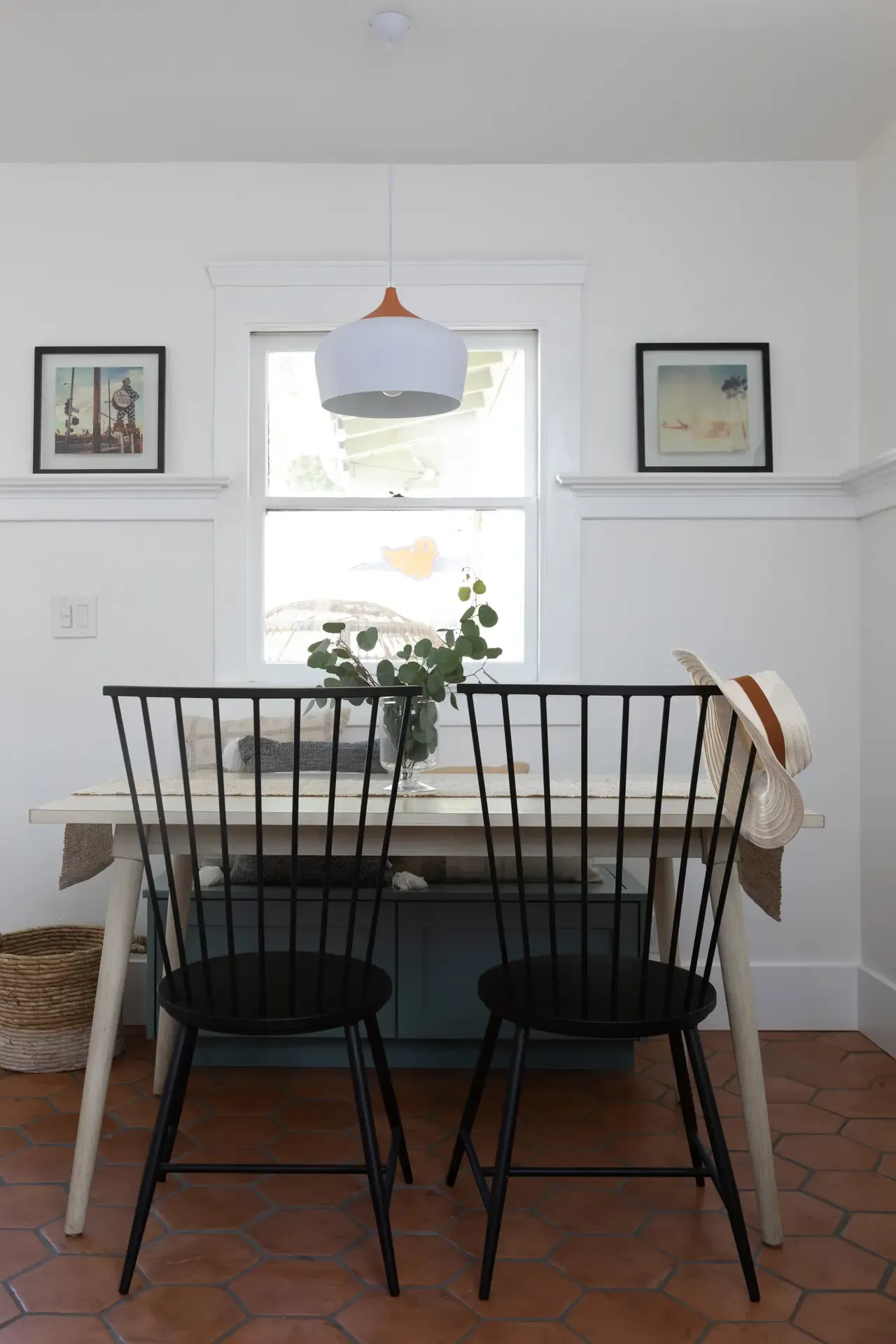 Bright breakfast nook with spindle-back chairs, terracotta hex floor, and white wainscoting